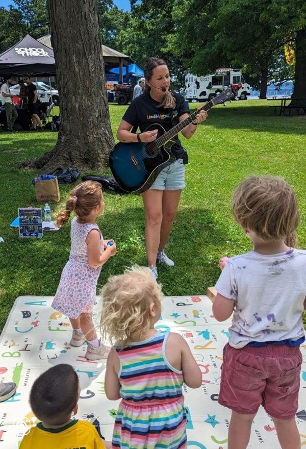 woman with guitar singing to kids
