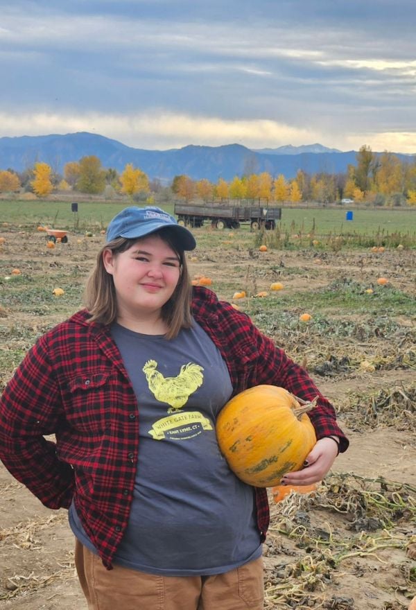 kid holding pumpkin under arm at pumpkin patch