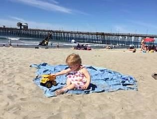 Child plays in the sand near Oceanside Pier beach