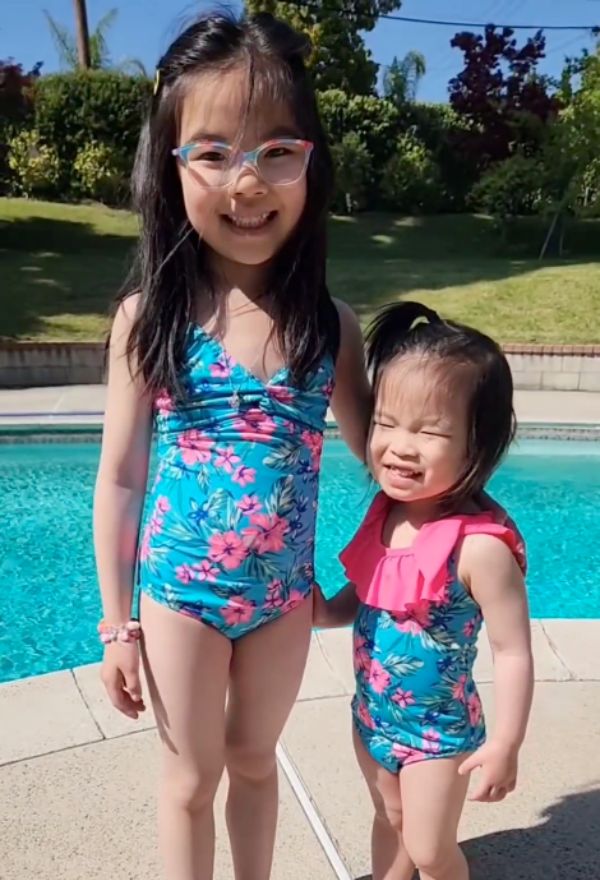 two girls in coordinating swimsuits standing beside a pool