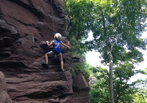 Child rock climbing outdoors with Philadelphia Rock Gyms camp
