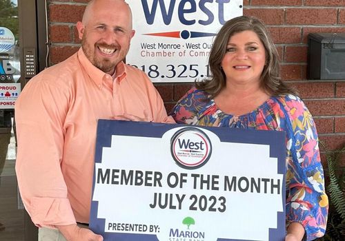 Kristopher Kelly West Monroe Chamber President with Missy Robertson, Macaroni Kid publisher holding a sign indicating Macaroni KID is the Member of the Month