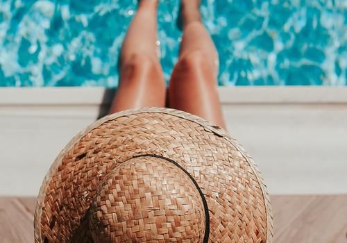 Woman sitting poolside with hat