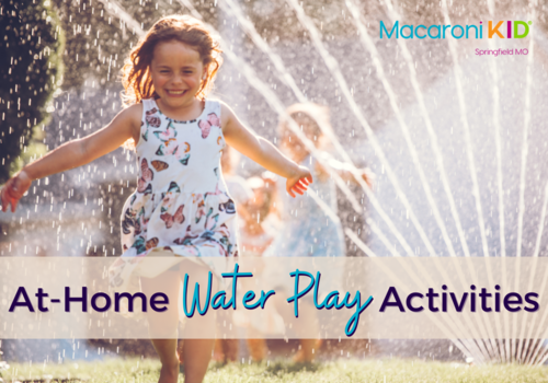 Kids playing in a backyard with a water sprinkler. Little girl running through the water smiling wearing a dress with butterflies. Text reads At Home Water Play Activities