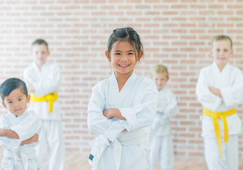 Five kids in taekwondo class smiling at the camera