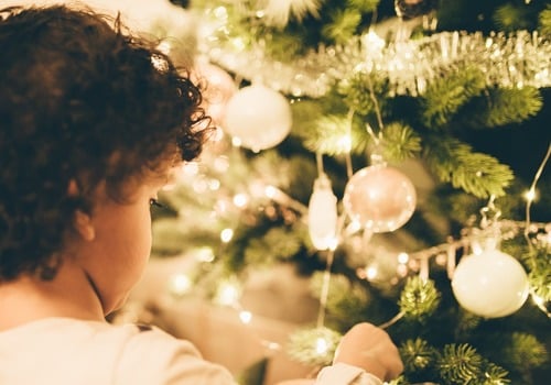 child putting ornaments on Christmas tree holiday