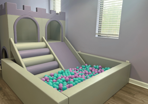 Ball Pit with green and purple balls. There is a castle like structure with a slide that drops into the ball pit.