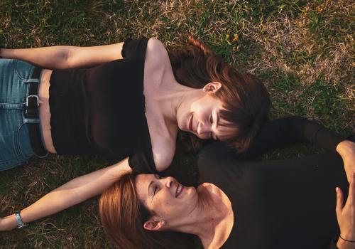 Mother and daughter laying in field