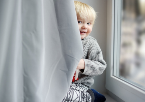 Child peeking from behind curtain