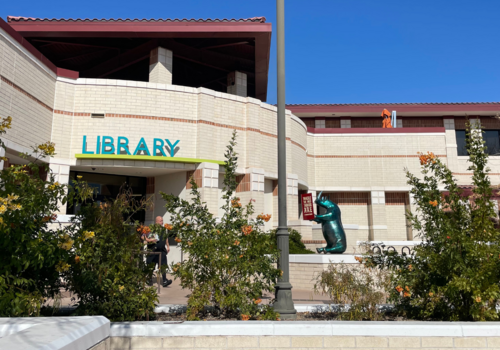Peoria Library Entrance with bushes and Rhino reading a book sculpture