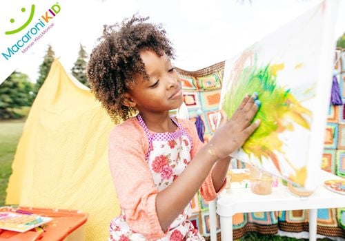 A child finger painting outside at an art festival.