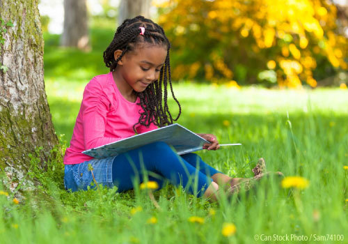 Young girl reading under a tree