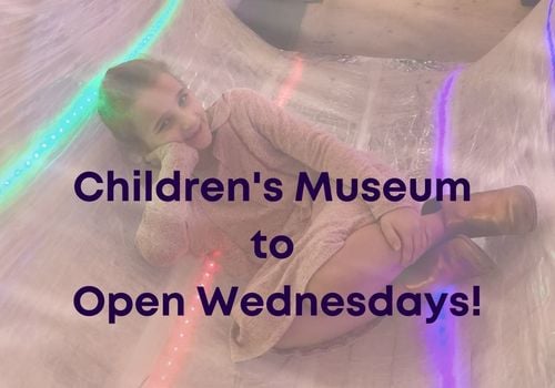Little girl posing in Tape Scape exhibit with wording stating Children's Museum to open Wednesdays