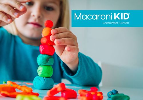 A young child stacking colorful balls of play dough.
