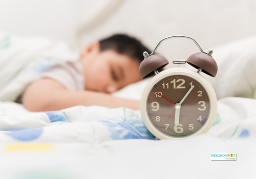 kid sleeping. alarm clock in foreground