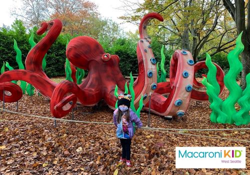 Large octopus sculpture in background with a small child standing in front
