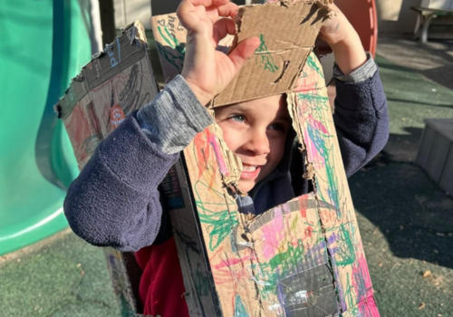 Young boy peeks out of a handmade costume