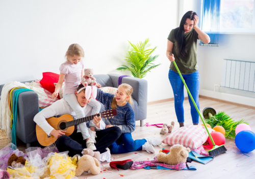 mom tries to clean messy living area while kids are oblivious to the chaos