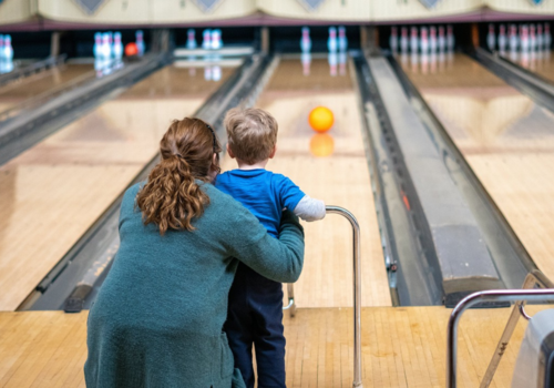 kid bowling with family