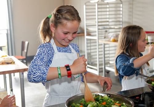 Girl smiling while cooking at Uncorked Kitchen in Centennial, Colorado.