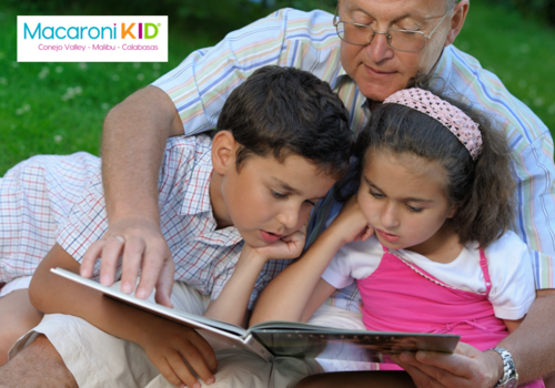 Grandfather reading to kids outdoors