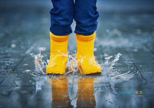 child jumping in puddle with yellow boots.
