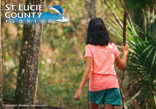 girl with walking stick walking on a nature trail