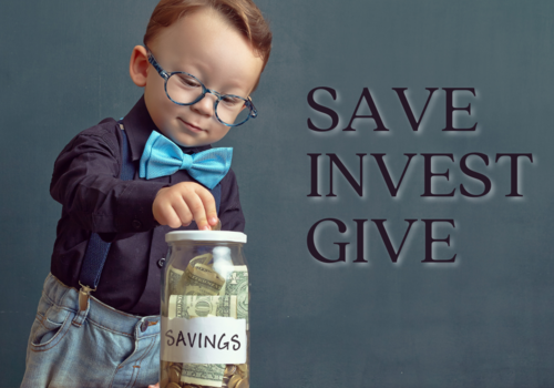 Toddler in a blue bow tie with glasses on saving money in a money jar as he learns to save, invest, and give back money