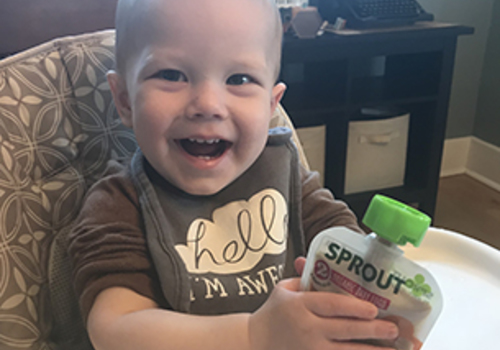 Baby holding Sprout baby food pouch