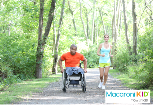 man in wheelchair on jogging trail next to jogging woman