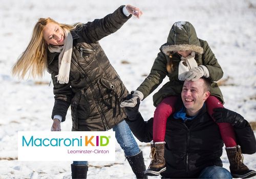 Two adults and one child laughing and playing in the snow.
