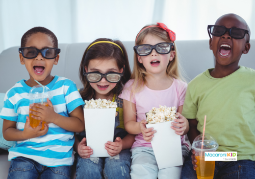 Happy kids enjoying popcorn and drinks while sitting