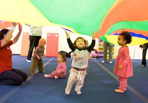 toddlers enjoying parachute with instructor