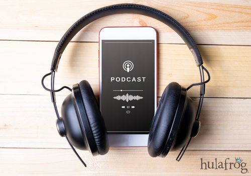 phone playing a podcast with headphones on wood background