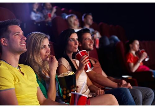 Group of people watching a movie, eating popcorn, and sipping drinks