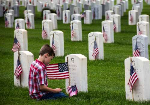 Young boy placing flags at headstones, Memorial Day