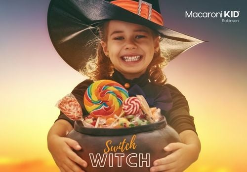 Little girl dressed in a witch costume holding a cauldron of candy