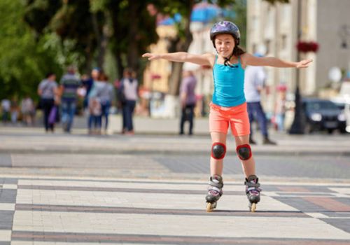 Little girl in inline skates rolling down the sidewalk