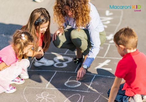 Mom and kids drawing hopscotch with chalk