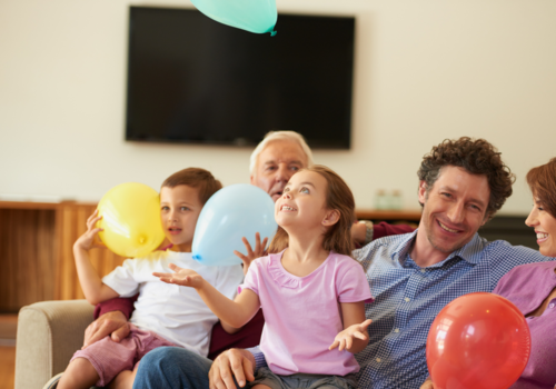 Family smiling on couch holding balloons