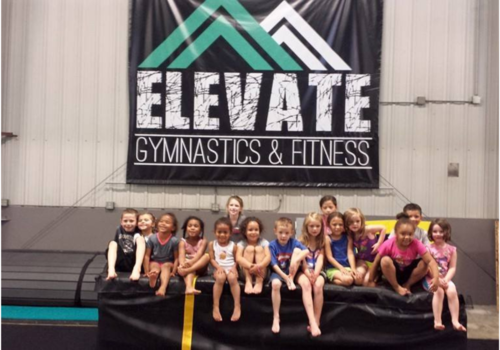 kids sitting on a mat at Elevate Gymnastics