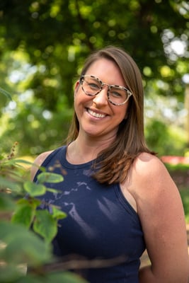 Fair skinned woman with brown hair and glasses smiling