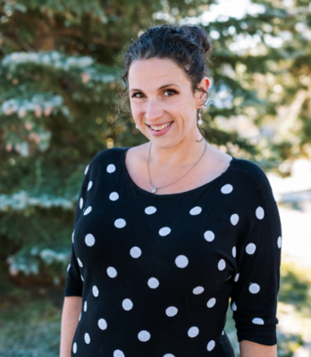 Woman in polka dot sweater in front of pine tree