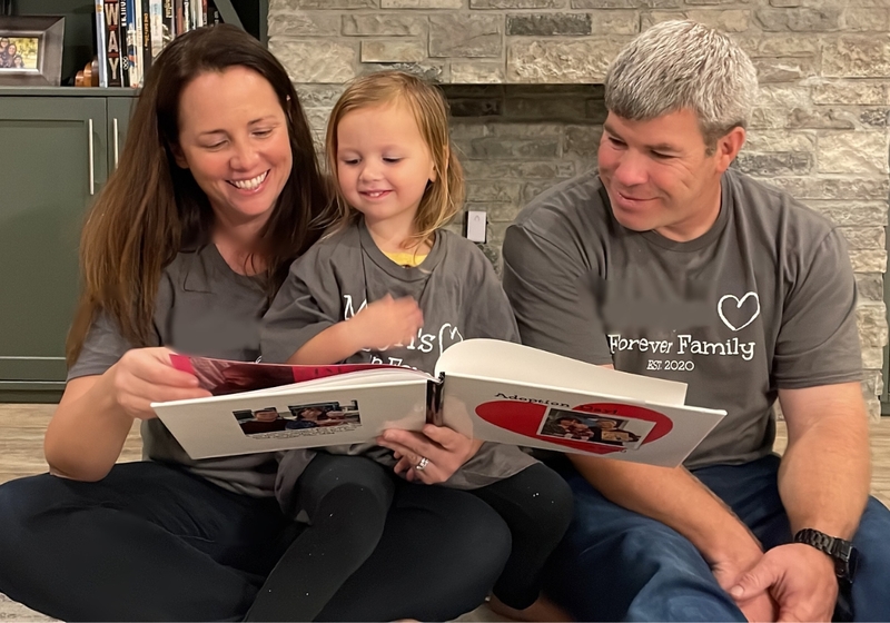 Adoption: Family in Gray Shirts Looking at Adoption Story Book