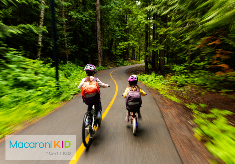 Kids biking to school on a pathway through a lush forest. Bike to school for a sustainable lifestyle. Sisters going to school.