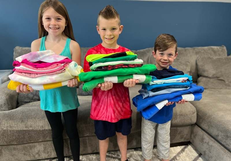 Kids holding stacks of Clothing Shop Online clothes