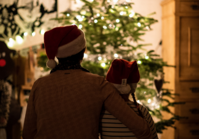 child and parent in front of Christmas tree