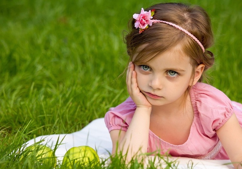 little girl in grass looking bored