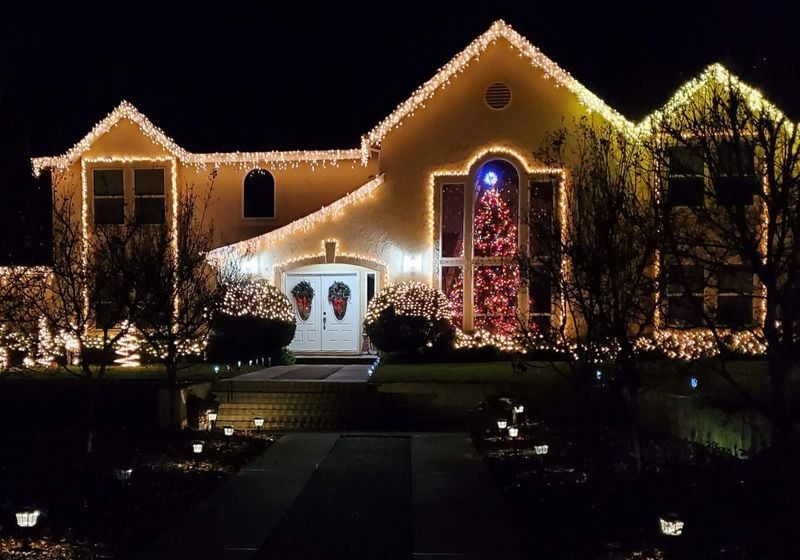 A big home with a very tall Christmas tree in the window