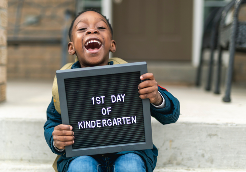 Happy Child holding First day of kindergarten sign